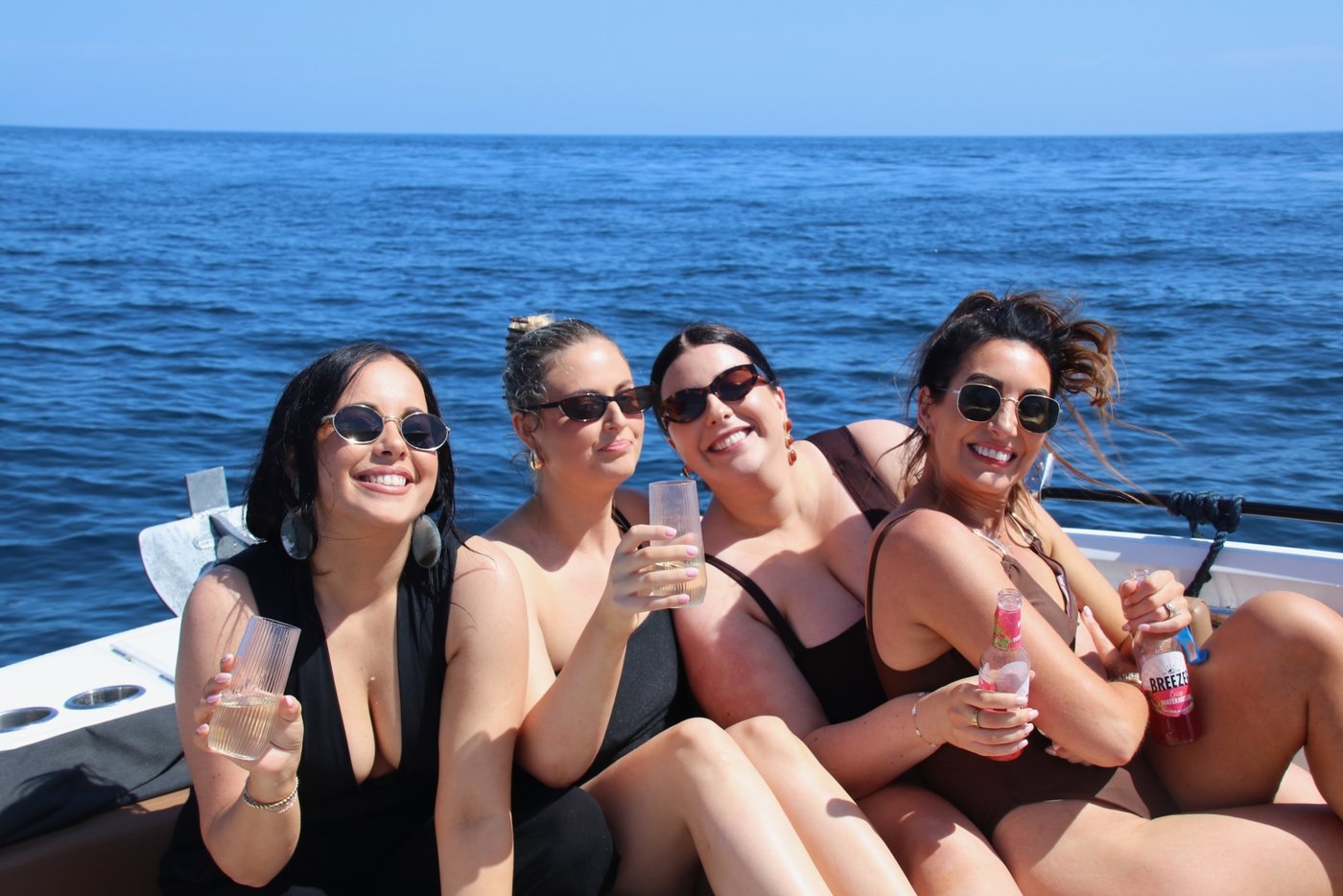 Four friends raising their glasses on deck on a birthday charter